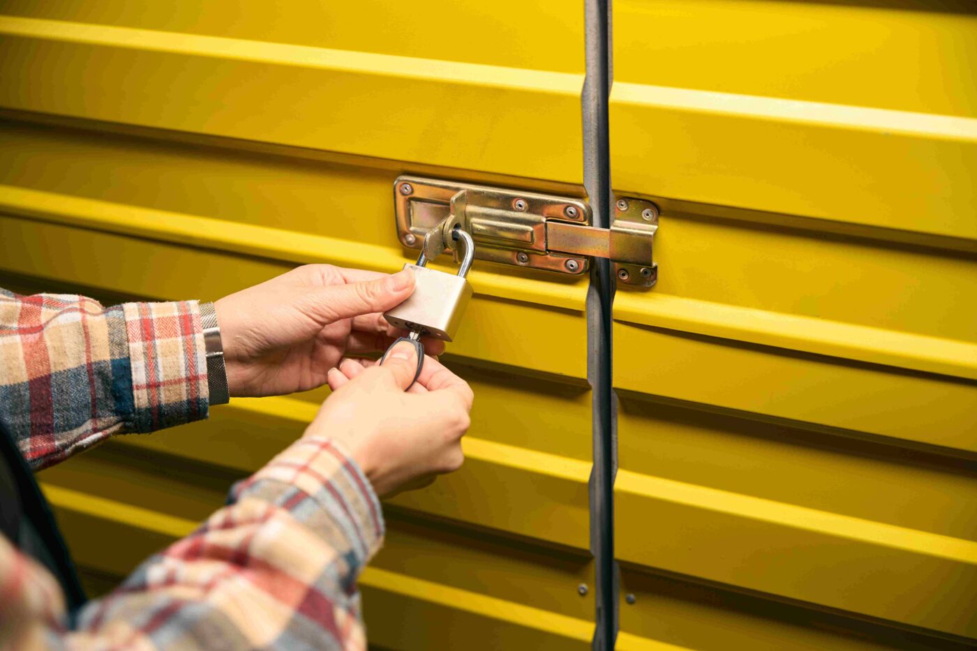 A man locks up his self storage container using a padlock.