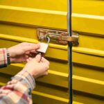 A man locks up his self storage container using a padlock.